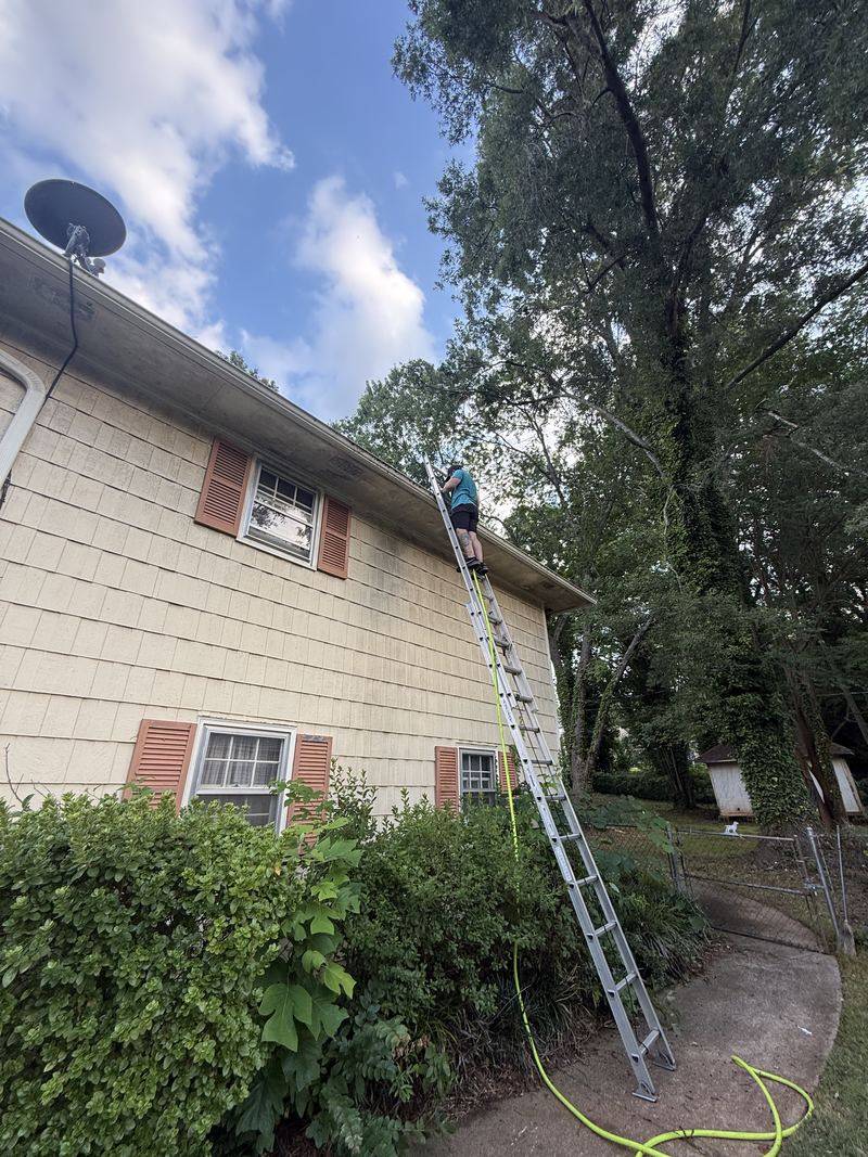 Ladder set against the eave of a home for gutter and siding cleaning