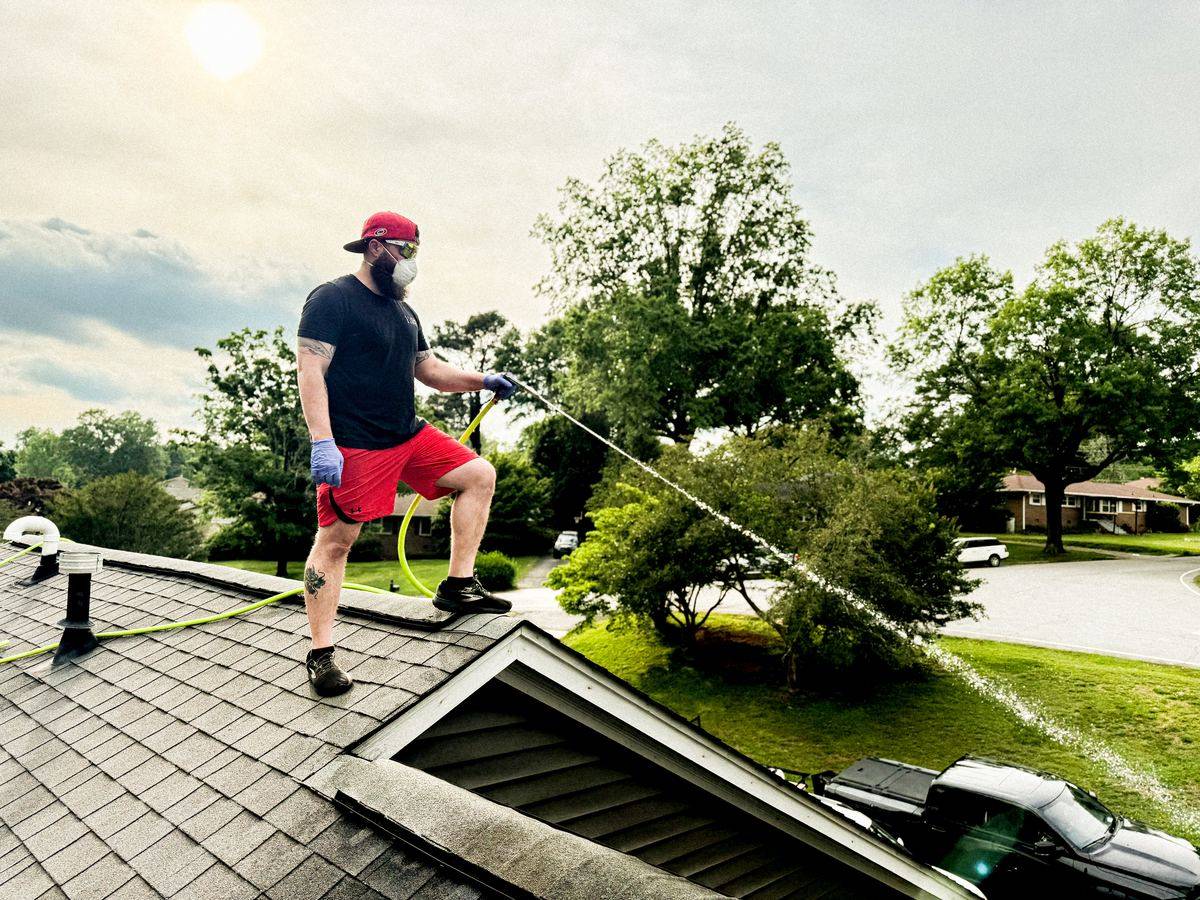 Moss Free technician soft washing an asphalt shingle roof on a home in Upstate South Carolina